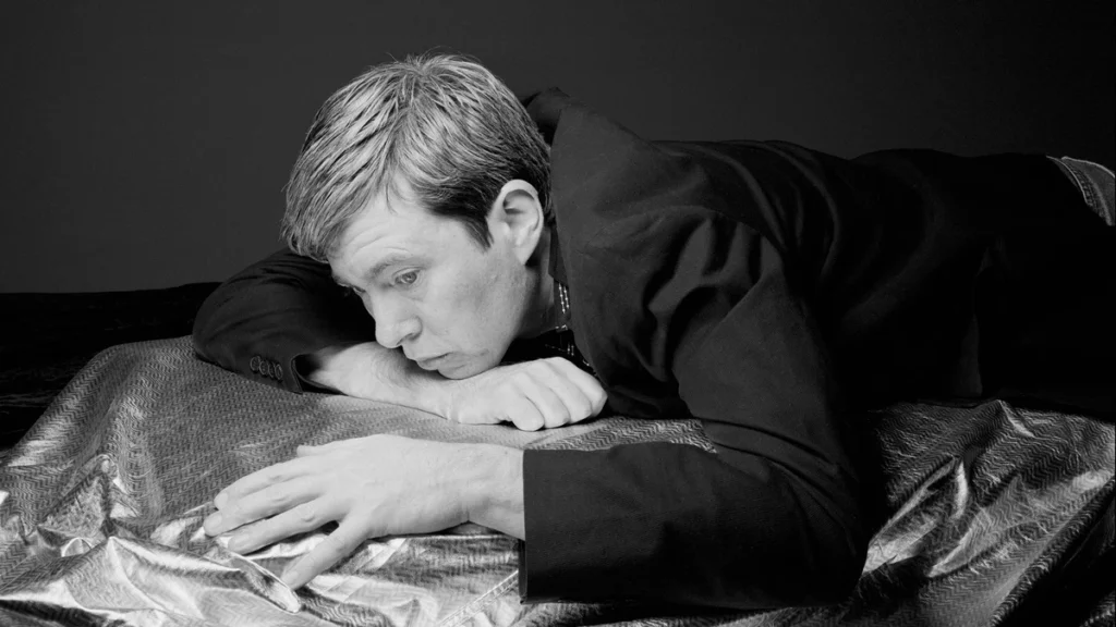 Black and white portrait of Bill Callahan resting on a metallic sheet