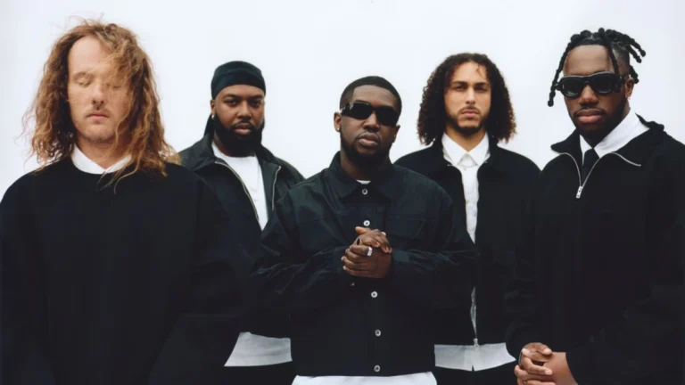 Ezra Collective's five members stand in black against a white backdrop